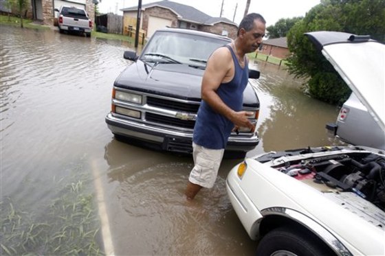Gus Lopez checks one of his vehicles as the water begins to recede in the Las Colonias Subdivision in Corpus Christi, Texas, on Monday.